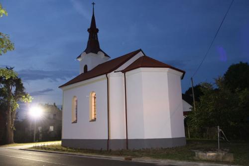 Místní kaple je v&nbsp;nočních hodinách osvětlena. Pohled na&nbsp;její zadní část a&nbsp;nové osvětlení